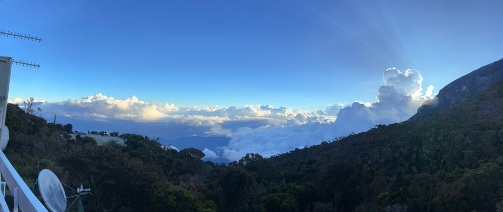 Sunset view from Laban Rata balcony with clouds drifting over mountains and sun rays shining onto forest below, at Panalaban Base Camp, Mount Kinabalu. © SlowingwithT.com