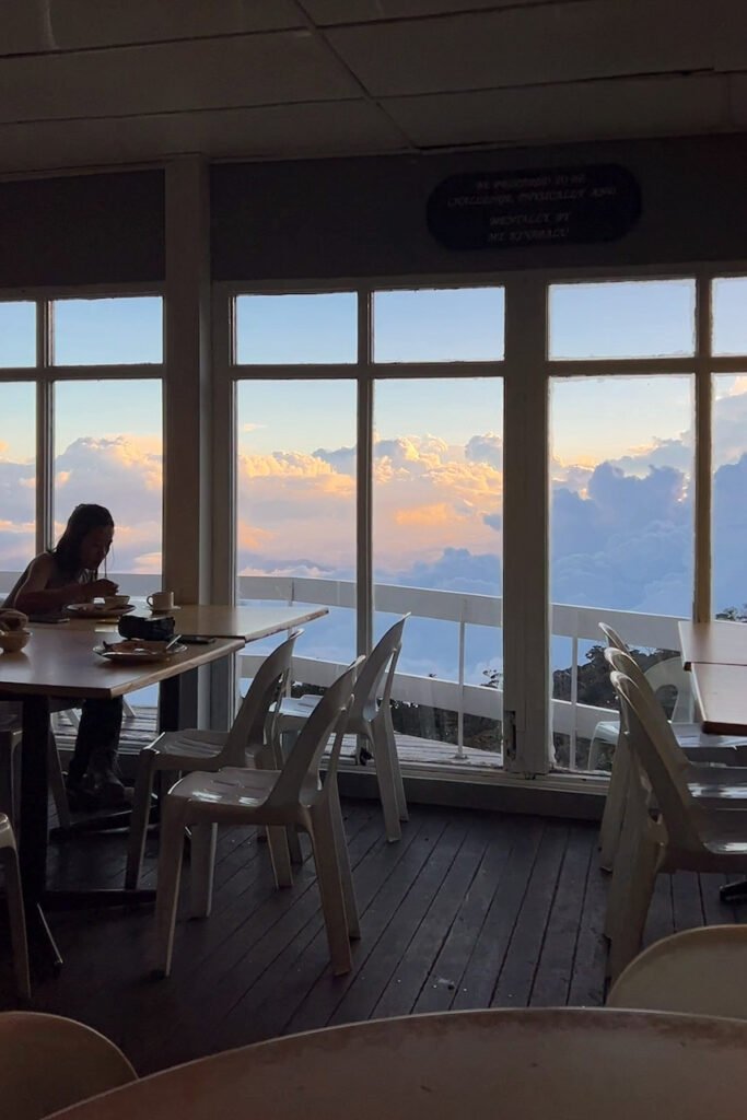 Laban Rata dining hall with floor to ceiling windows and trekkers eating during Mount Kinabalu climb. © SlowingwithT.com